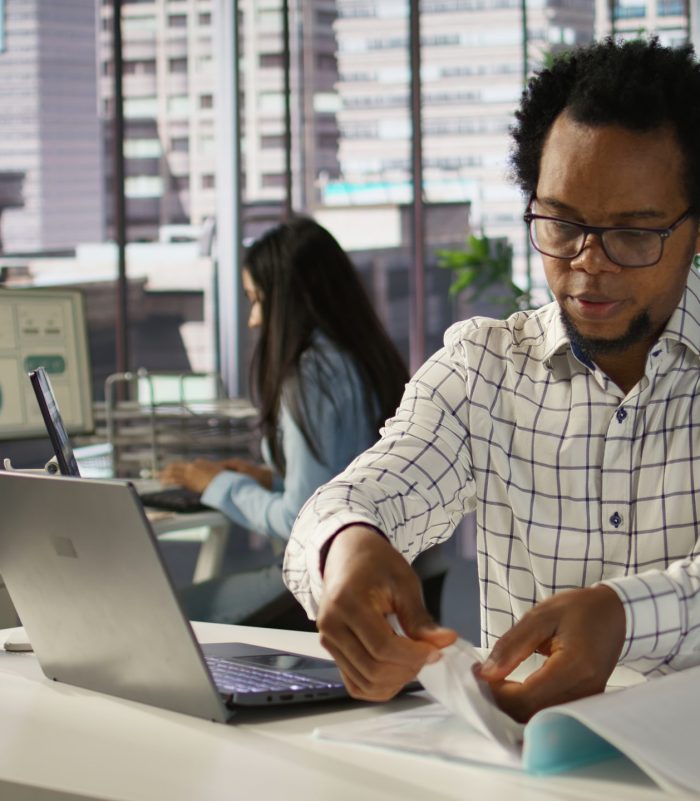 Successful entrepreneur working on financial forecasts at his desk, using data and technology to manage business tasks and project development. Company progresses toward its goals. Camera B.